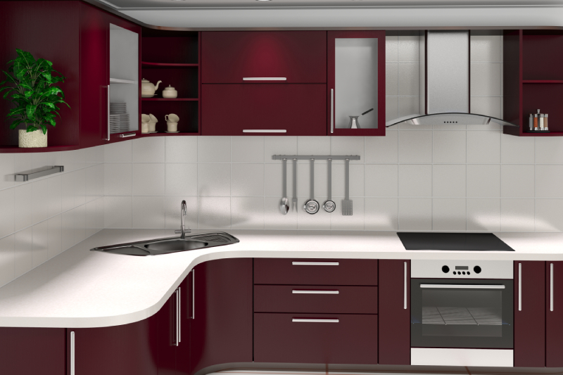 A modern kitchen setup with maroon cabinets, white countertops, a built-in oven, induction cooktop, modular sink, chimney, and stainless steel appliances.